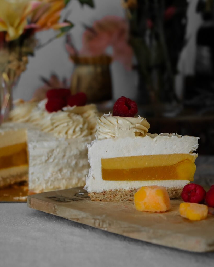 Erfrischende leckere Mango-Kokos-Mousse-Torte mit einer luftigen Kokoscreme und frischen Mangostücken und exotischer Mangocreme und Pfirisch Ganache als Aufschlagganache im Schnitt