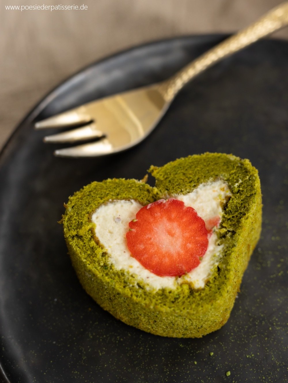 Ein frühlingshaftes Stück Matcha Swiss Roll Biskuit mit einem Schnitt durch die Pistazienganache Füllung und einer roten Erdbeere. Perfekt für die Ostertafel